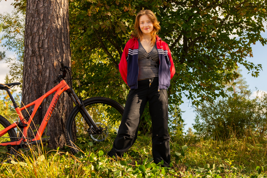 En elev på Äventyrsgymnasiet i Älvdalen står vid ett träd med en mountainbike.